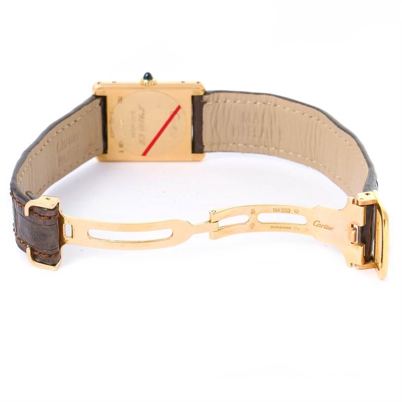 This image shows the backside of the Cartier Tank Classic Yellow Gold Silver Dial Yellow Gold Silver Dial watch along with its leather strap and gold deployant clasp.