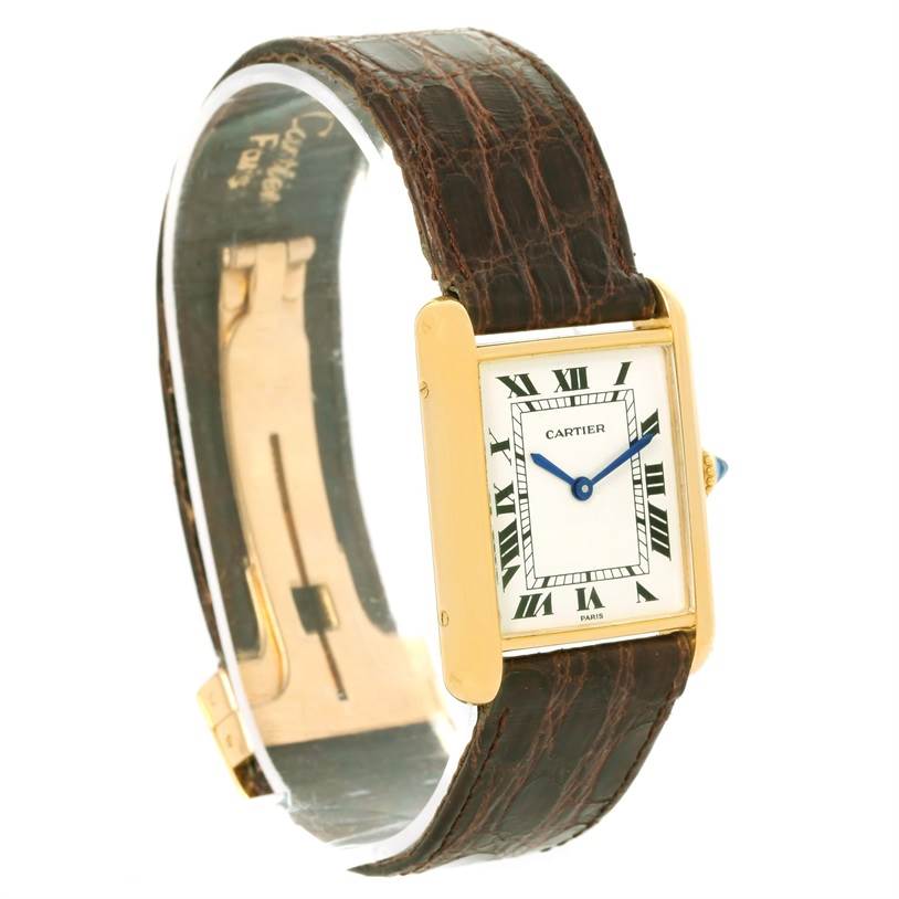 This image features a Cartier Tank Classic Men
s Yellow Gold White Dial Men
s Yellow Gold White Dial watch at a slight angle, displaying its rectangular face, brown leather strap, and gold case.