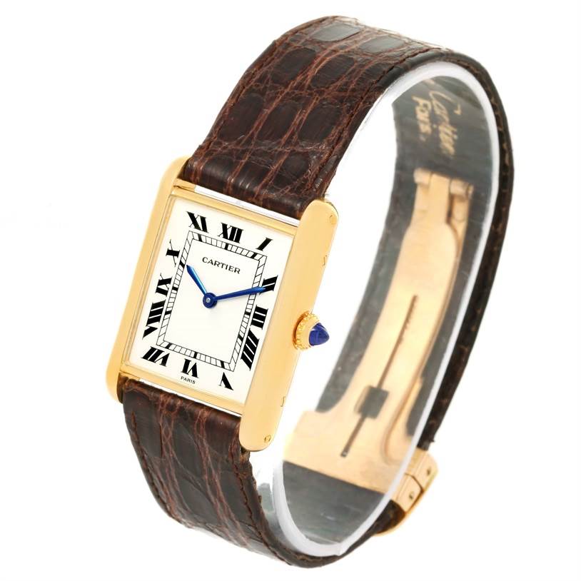 The Cartier Tank Classic Men
s Yellow Gold White Dial Men
s Yellow Gold White Dial watch is shown at an angled view, displaying the face, leather strap, and part of the clasp.