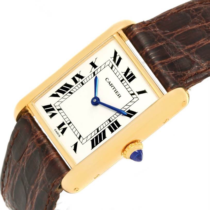 The Cartier Tank Classic Men
s Yellow Gold White Dial Men
s Yellow Gold White Dial watch is shown at a slight angle, highlighting its face, blue hands, crown with blue gem, and leather strap.