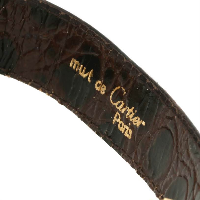 The image shows a close-up view of the Cartier Tank Classic Men
s Yellow Gold White Dial Men
s Yellow Gold White Dial watch
s leather strap with "must de Cartier Paris" inscribed.