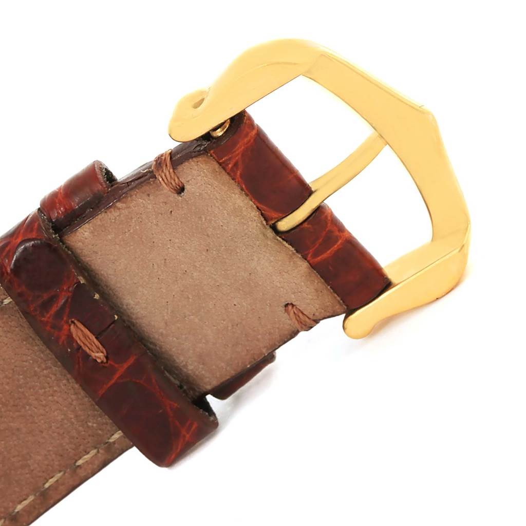 The image shows a close-up of the leather strap and gold buckle of a Cartier Tank Classic Yellow Gold White Dial Yellow Gold White Dial watch.