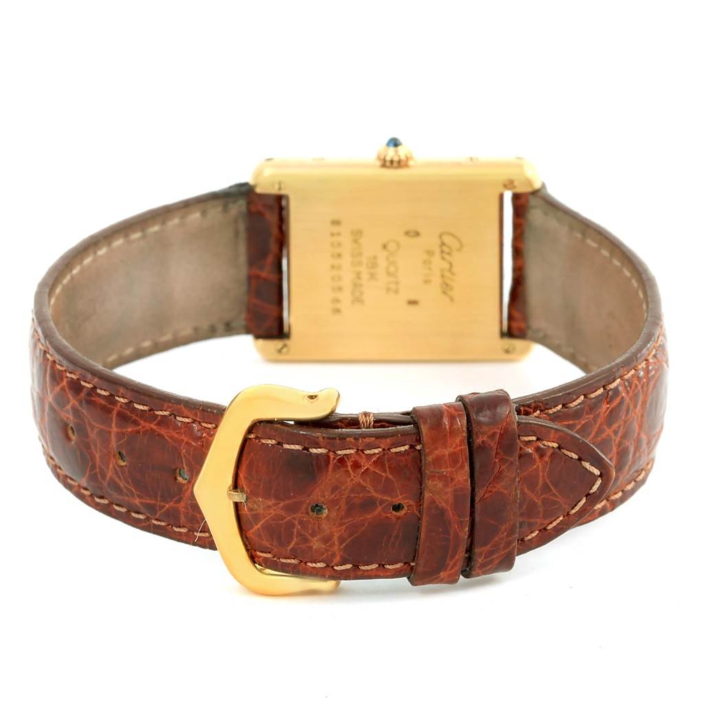 The image shows the back view of a Cartier Tank Classic Yellow Gold White Dial Yellow Gold White Dial watch, focusing on its leather strap and gold buckle.