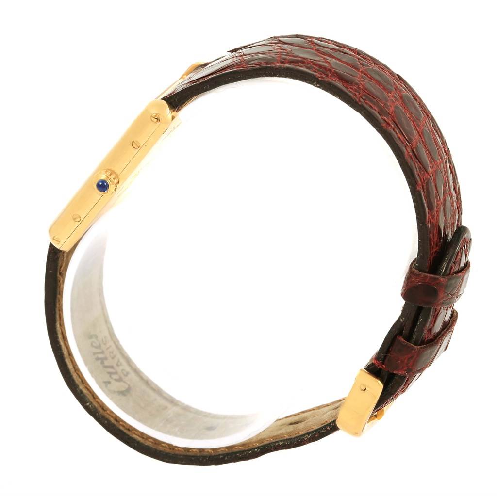 The image shows a side angle of the Cartier Tank Classic 1140 Yellow Gold White Dial 1140 Yellow Gold White Dial watch, highlighting its gold case, blue cabochon crown, and brown leather strap.