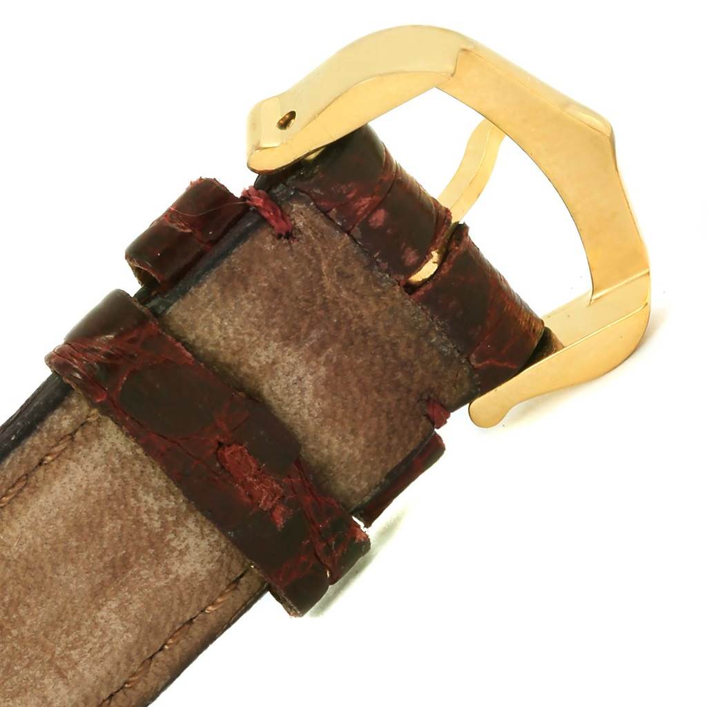 The image shows a close-up of the leather strap and gold buckle of the Tank Classic model watch by Cartier.