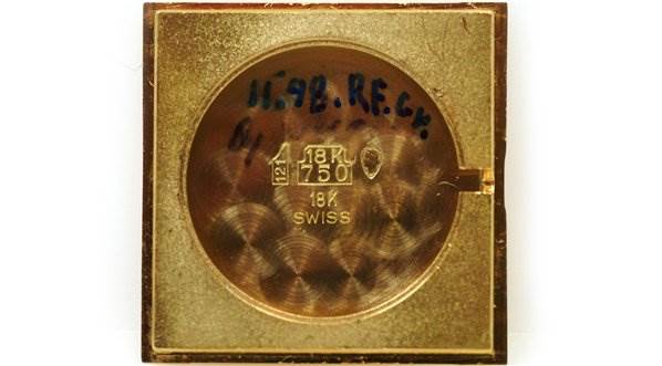 This image shows the back plate of a Cartier Tank Classic Men's Yellow Gold White Dial Men's Yellow Gold White Dial watch, displaying inscriptions and hallmarks.
