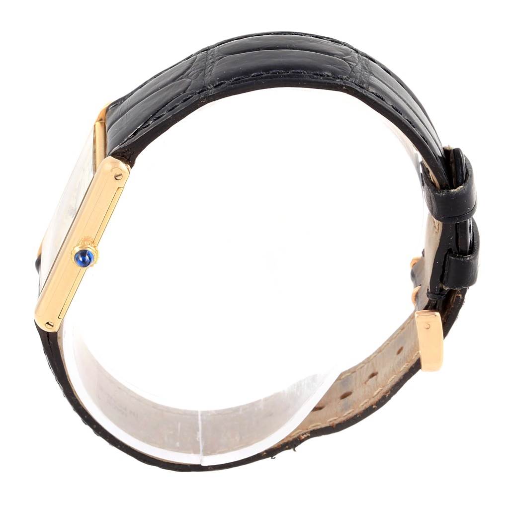 The image shows a side view of a Cartier Tank Classic Men's Yellow Gold White Dial Men's Yellow Gold White Dial watch, highlighting the gold case, crown, and black leather strap.