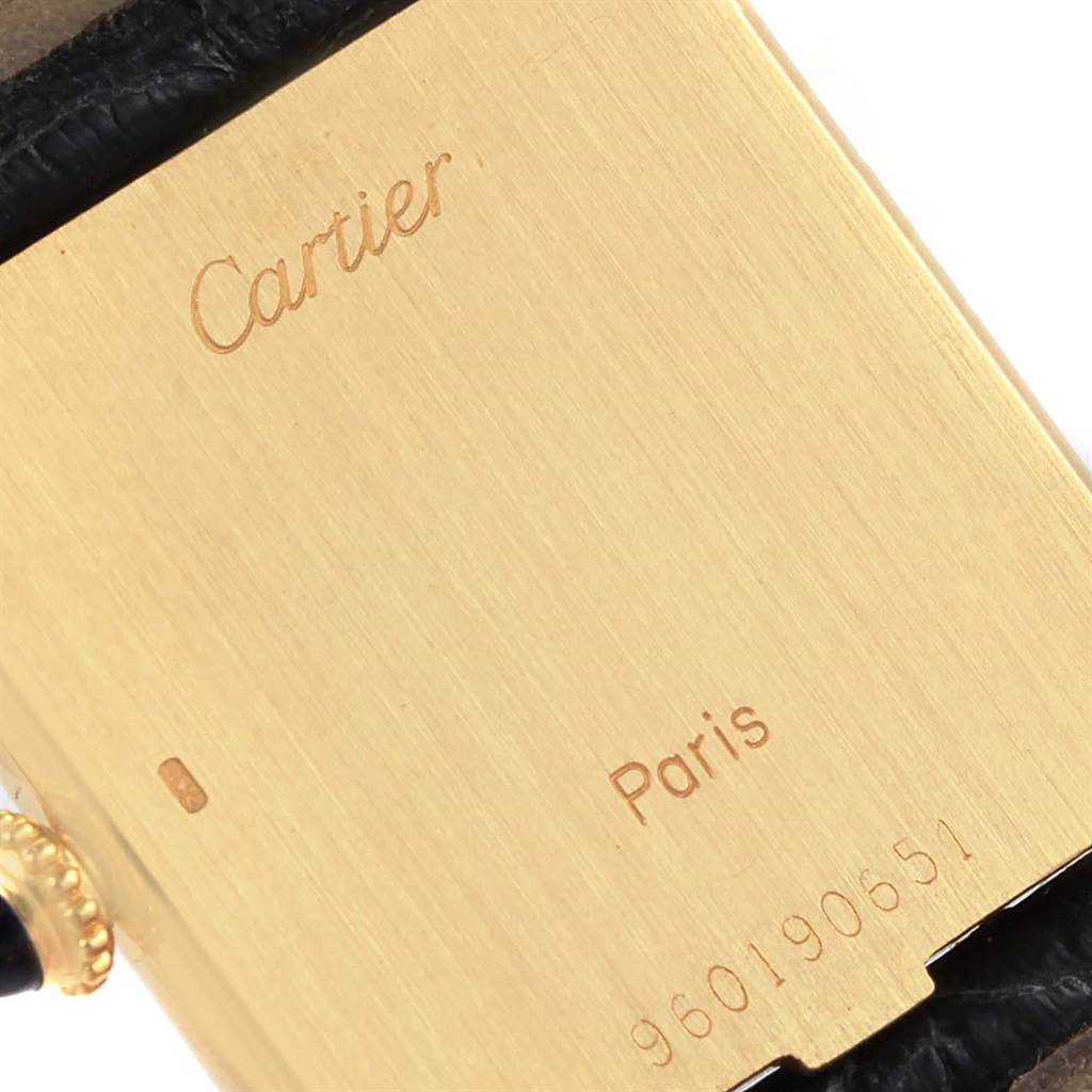 This image shows a close-up of the back of a Cartier Tank Classic Men's Yellow Gold White Dial Men's Yellow Gold White Dial watch with engravings visible.