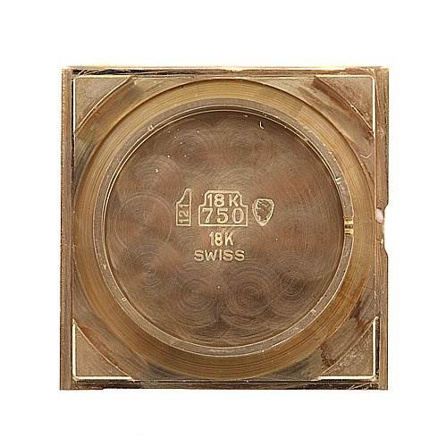 This image shows the back case of a Cartier Tank Classic Yellow Gold White Dial Yellow Gold White Dial watch, featuring engravings of 18K gold and Swiss markings.