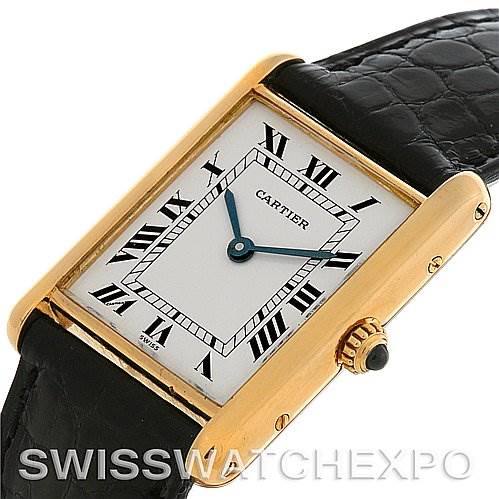 The image shows an angled close-up of the Cartier Tank Classic Yellow Gold White Dial Yellow Gold White Dial watch, highlighting its face, bezel, and part of the black leather strap.