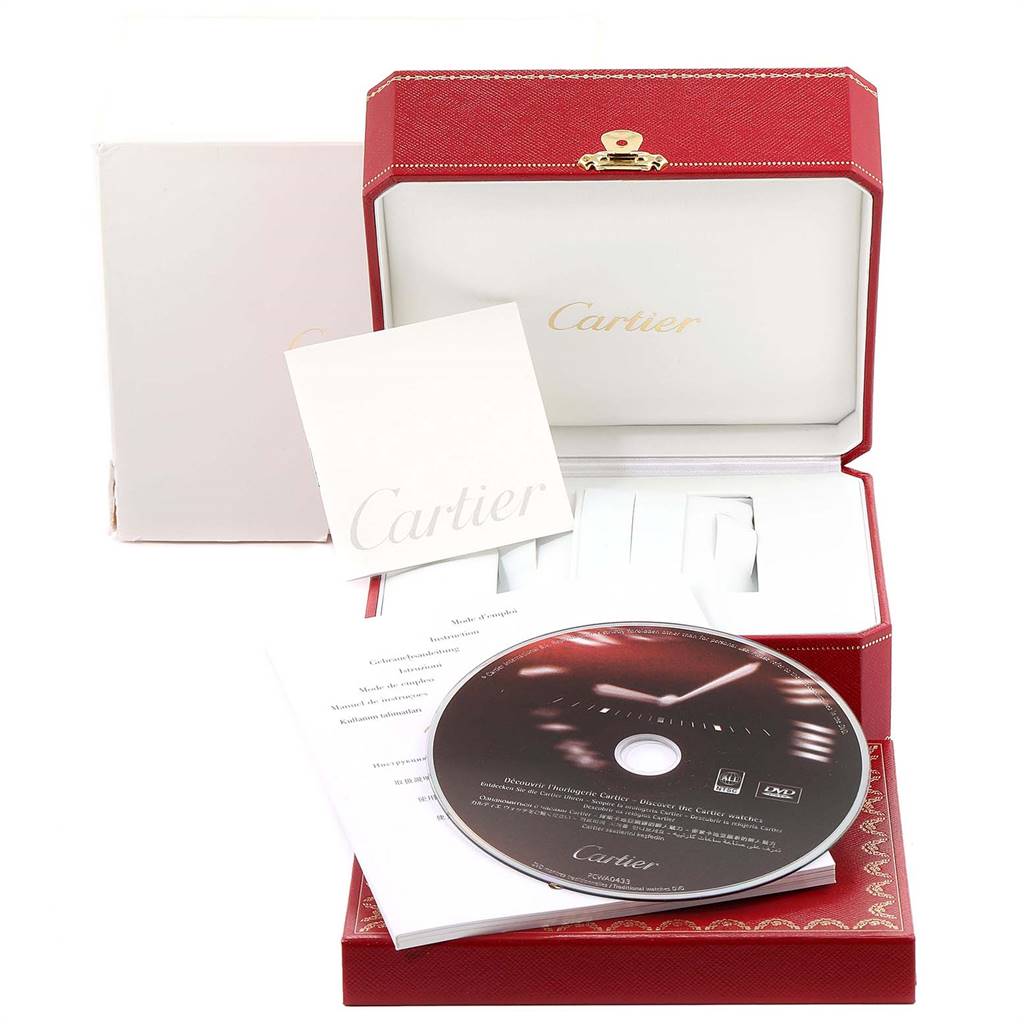 The image shows the packaging of a Cartier Tank Classic Men
s Yellow Gold Silver Dial Men
s Yellow Gold Silver Dial watch, including its red case, outer box, booklet, and CD.
