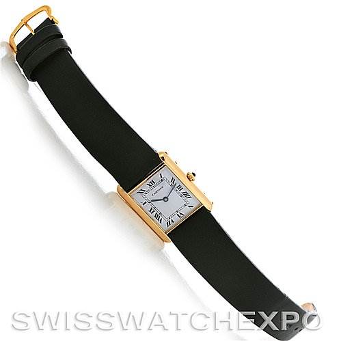 This image shows a top-down view of a Cartier Tank Classic Yellow Gold White Dial Yellow Gold White Dial watch with a black strap and a rectangular gold case.