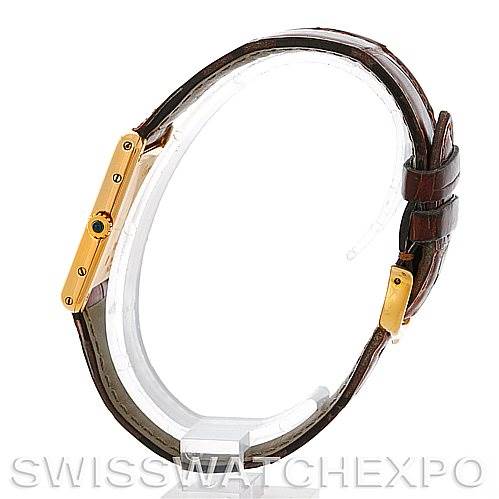 Side view of the Tank Classic model by Cartier, showcasing the watch's golden case, brown leather strap, and crown with a blue gemstone.