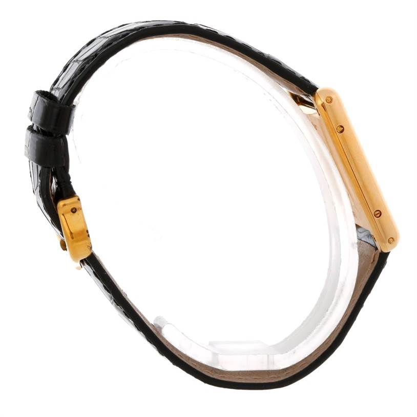 The image shows a side profile of a Cartier Tank Classic Men's Yellow Gold White Dial Men's Yellow Gold White Dial watch, highlighting its gold rectangular case and black leather strap.