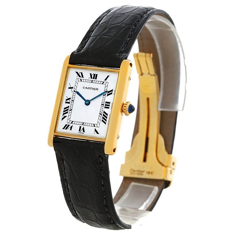 The Cartier Tank Classic Men's Yellow Gold White Dial Men's Yellow Gold White Dial watch is shown at a slight angle, showcasing its rectangular face, black leather strap, and gold casing.