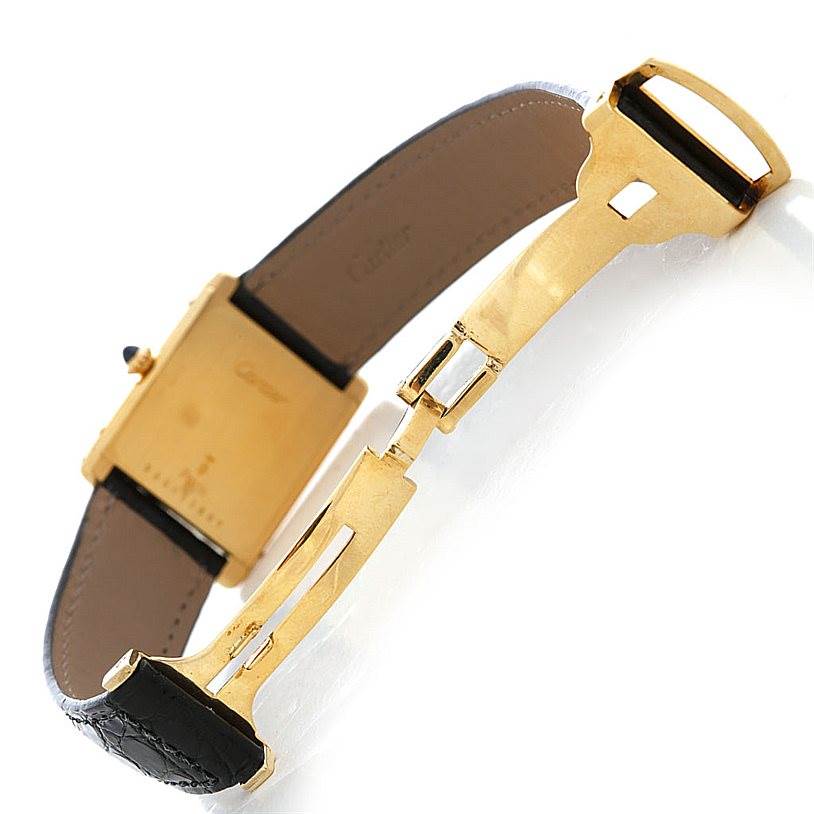 The image shows the back side of a Cartier Tank Classic Men's Yellow Gold White Dial Men's Yellow Gold White Dial watch including its case back and partially open leather strap with a deployant clasp.