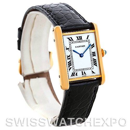 This image shows a Cartier Tank Classic Men
s Yellow Gold Silver Dial Men
s Yellow Gold Silver Dial watch at a three-quarter angle, highlighting its gold case, white dial, and black leather strap.