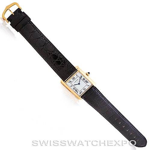 The image shows an overhead view of a Cartier Tank Classic Men's Yellow Gold White Dial Men's Yellow Gold White Dial watch with a black leather strap and a rectangular gold case.