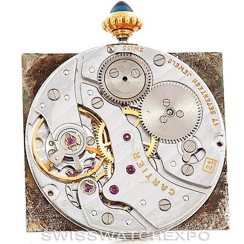 The image shows an internal mechanism view of the Cartier Tank Classic Men's Yellow Gold Silver Dial Men's Yellow Gold Silver Dial watch, focusing on its gears and movement components.