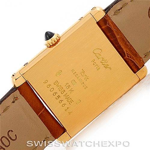 This image shows the back of a Cartier Tank Classic Men's Yellow Gold Silver Dial Men's Yellow Gold Silver Dial watch, highlighting the gold case, inscription, and part of the leather strap.