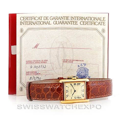 The image shows the Cartier Tank Classic W002953 Men's Yellow Gold Champagne Dial W002953 Men's Yellow Gold Champagne Dial watch laying flat, with an international guarantee certificate in the background.