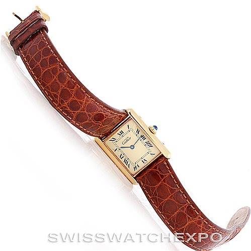 The Cartier Tank Classic W002953 Men's Yellow Gold Champagne Dial W002953 Men's Yellow Gold Champagne Dial watch is shown at an oblique angle, displaying its face, brown leather strap, and side crown.