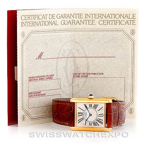 This image shows a Cartier Tank Classic W002953 Men's Yellow Gold White Dial W002953 Men's Yellow Gold White Dial watch at an angle displaying its face and strap, with its international guarantee certificate in the background.