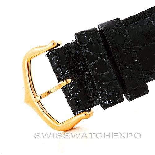 This image shows a close-up of the black leather strap and gold buckle of a Tank Classic model watch by Cartier.