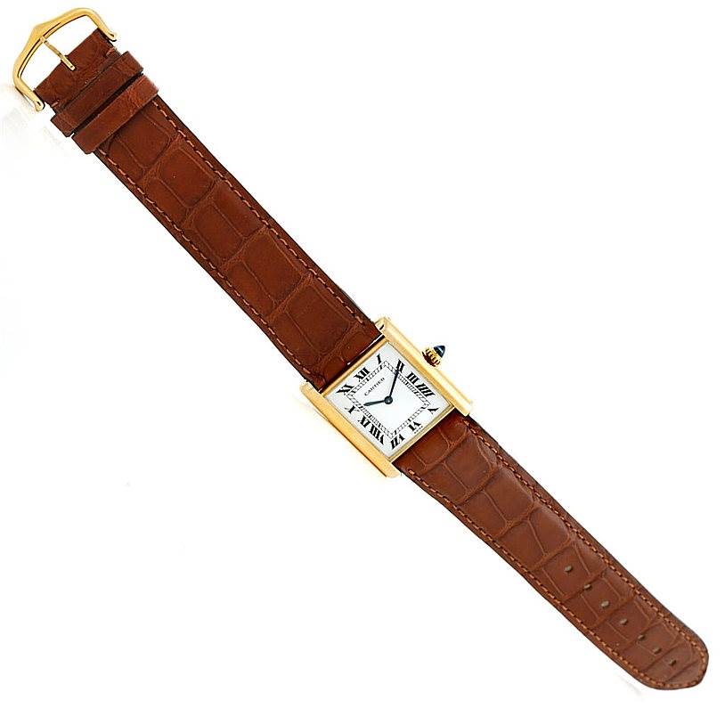 The Cartier Tank Classic Men
s Yellow Gold White Dial Men
s Yellow Gold White Dial watch, shown from a top view, features a rectangular dial, brown leather strap, and a gold casing.