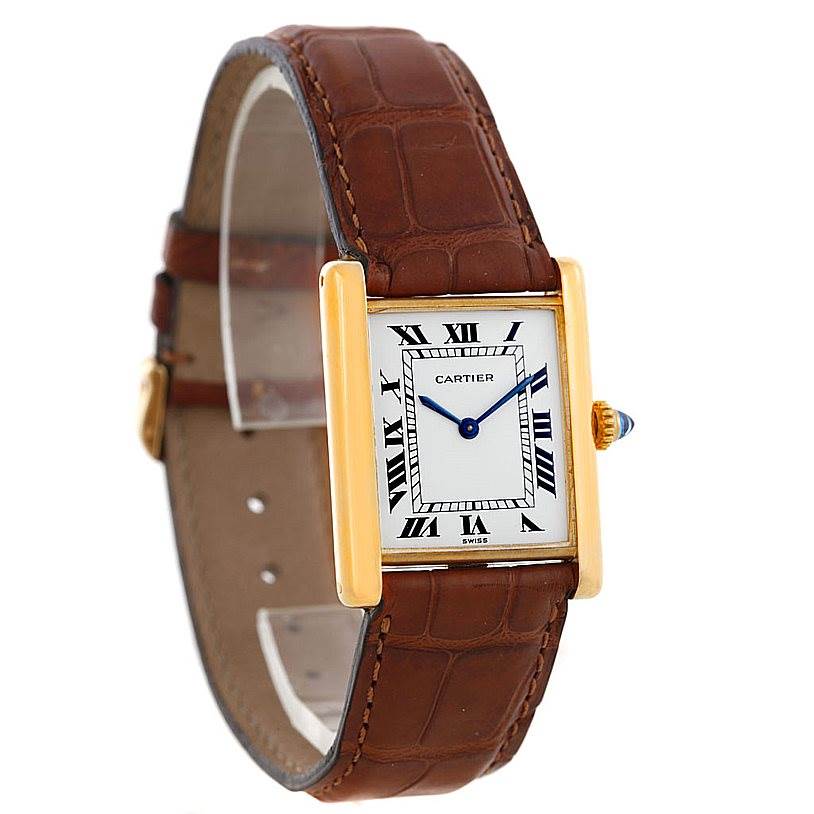 The Cartier Tank Classic Men
s Yellow Gold White Dial Men
s Yellow Gold White Dial watch is shown from a three-quarter angle, displaying the face, crown, and brown leather strap.
