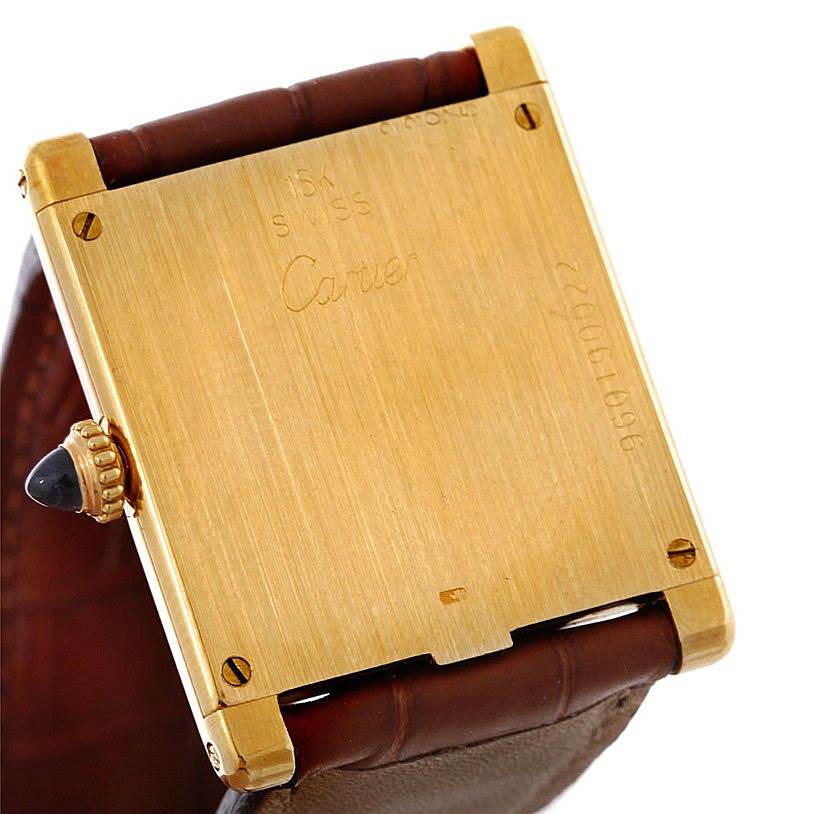 This image shows the back case and part of the leather strap of a Cartier Tank Classic Men
s Yellow Gold White Dial Men
s Yellow Gold White Dial watch.