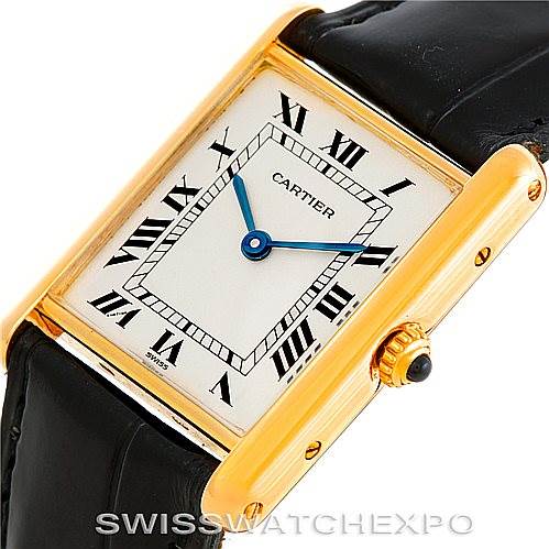 The image shows a close-up, angled view of the Cartier Tank Classic Men's Yellow Gold Silver Dial Men's Yellow Gold Silver Dial watch, highlighting its face, blue hands, and part of its black strap.