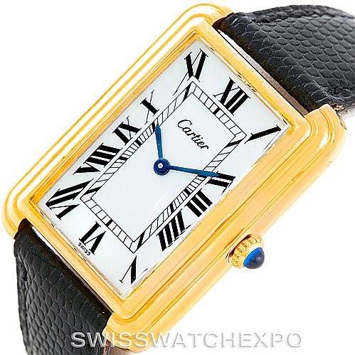 The image shows a close-up angle of the Cartier Tank Classic Men's Yellow Gold White Dial Men's Yellow Gold White Dial watch, highlighting its rectangular gold case, Roman numeral dial, blue hands, and black leather strap.