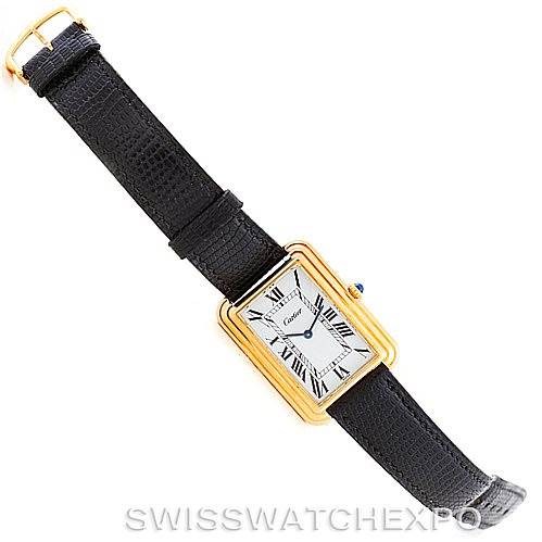 The image shows a top-down view of a Cartier Tank Classic Men's Yellow Gold White Dial Men's Yellow Gold White Dial watch with a black leather strap and a gold rectangular case.