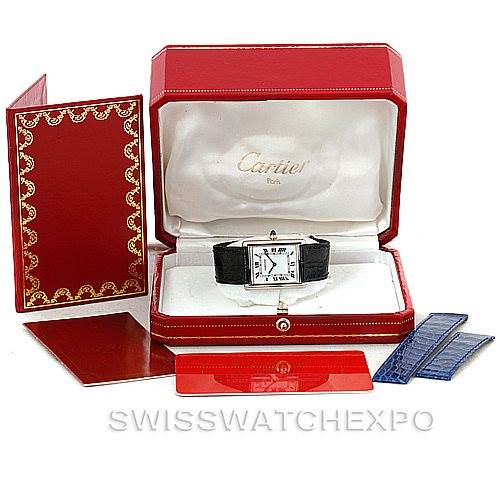 This image shows the Cartier Tank Classic Men's White Gold White Dial Men's White Gold White Dial watch at a front angle, displayed in an open red box with additional accessories like extra straps.