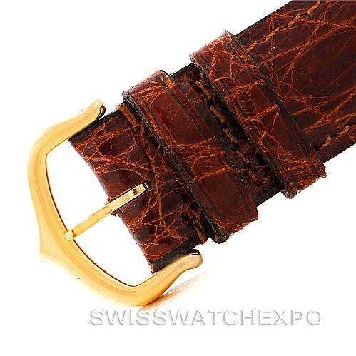 This image shows a close-up of the leather strap and gold-tone buckle of a Cartier Tank Classic Men's Yellow Gold Silver Dial Men's Yellow Gold Silver Dial model watch.