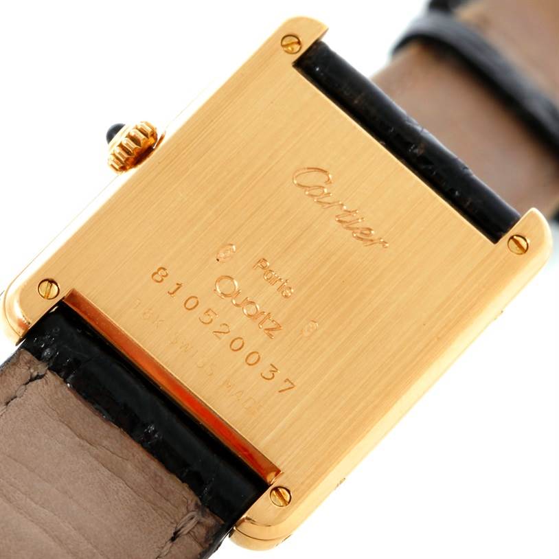 The image shows the back case of a Cartier Tank Classic Yellow Gold White Dial Yellow Gold White Dial watch, highlighting its inscriptions and leather strap.