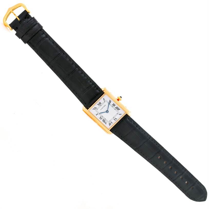 The image shows a Cartier Tank Classic Men's Yellow Gold White Dial Men's Yellow Gold White Dial model watch in a top-down angle, with a gold case and black leather strap.