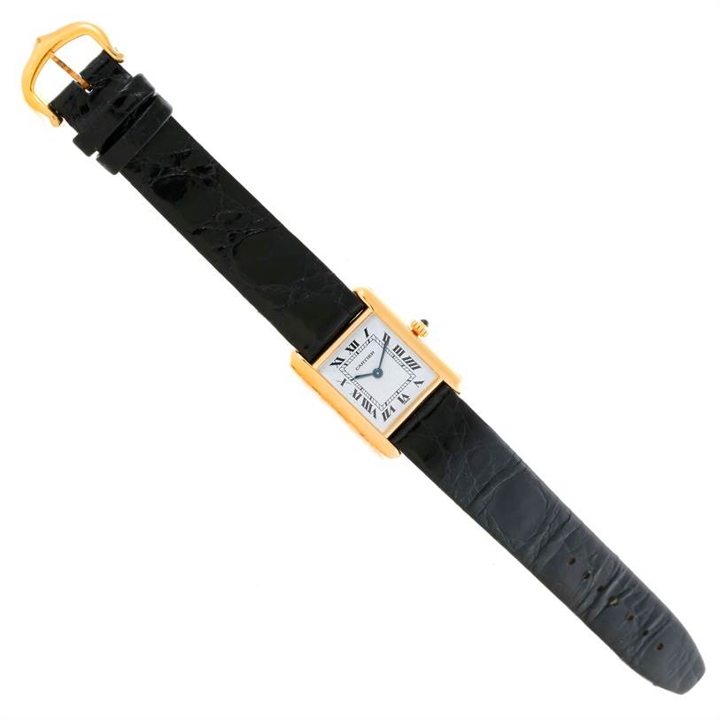 The image shows a Cartier Tank Classic Women's Yellow Gold White Dial Women's Yellow Gold White Dial watch laid flat, displaying its black leather strap and gold rectangular case with a white dial.