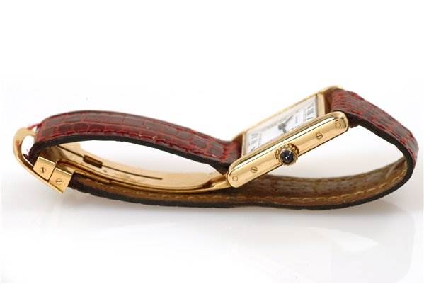 The image shows a Cartier Tank Classic Women's Yellow Gold White Dial Women's Yellow Gold White Dial watch from a side angle, highlighting its red strap and the winding crown with a blue gem.