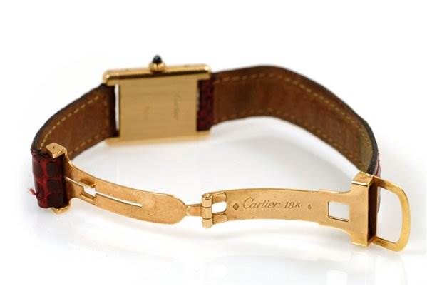 The image shows the underside of the Cartier Tank Classic Women's Yellow Gold White Dial Women's Yellow Gold White Dial watch, highlighting the clasp and part of the leather strap.