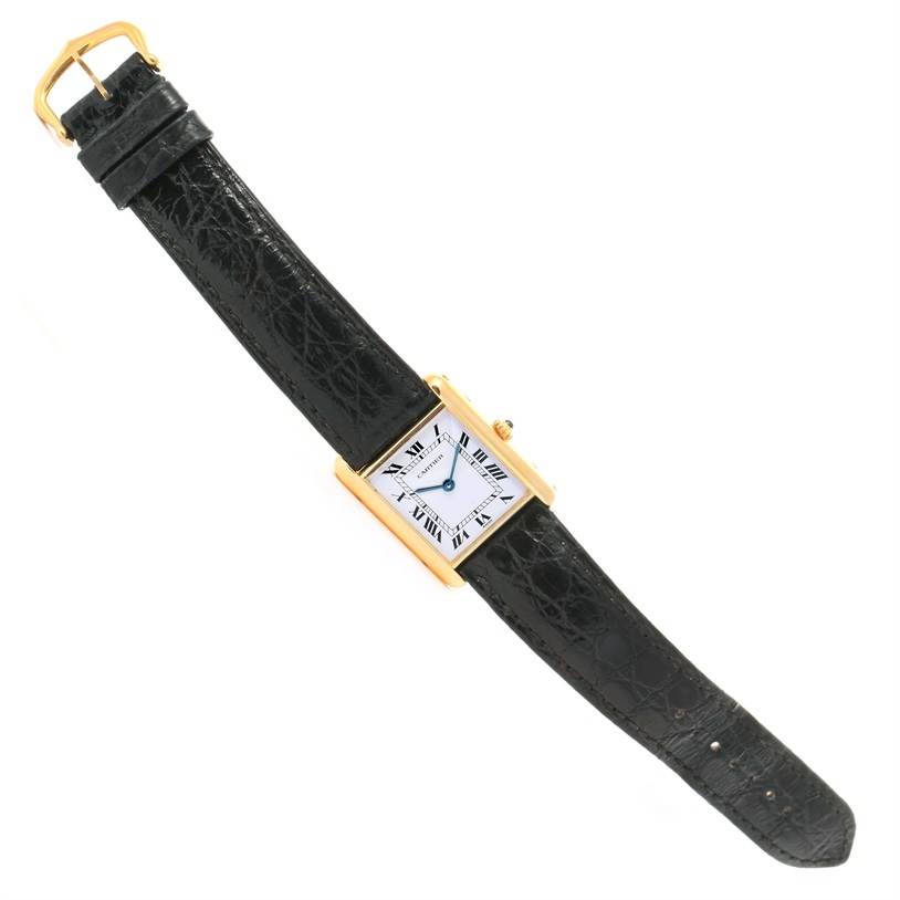 This image shows a full view of a Cartier Tank Classic Yellow Gold White Dial Yellow Gold White Dial watch with a black leather strap and a rectangular face.