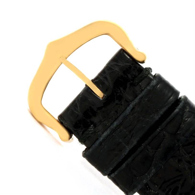 This image shows a close-up of the gold buckle and black leather strap of the Cartier Tank Classic Yellow Gold White Dial Yellow Gold White Dial watch.