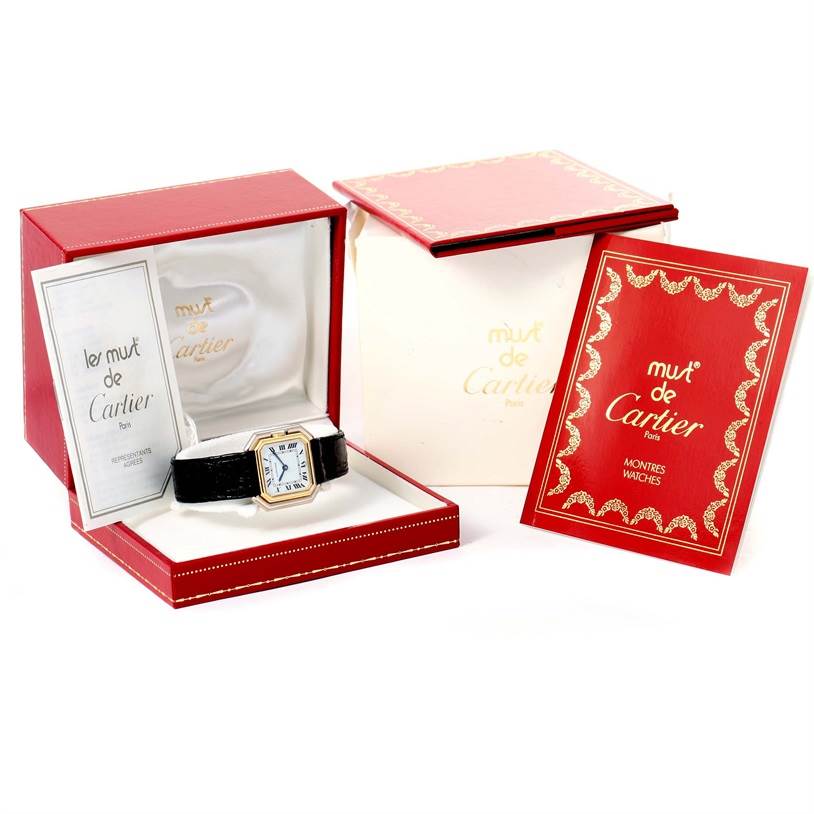 The image shows a Tank Classic model by Cartier in its packaging, with a red box, manual, and cushion.