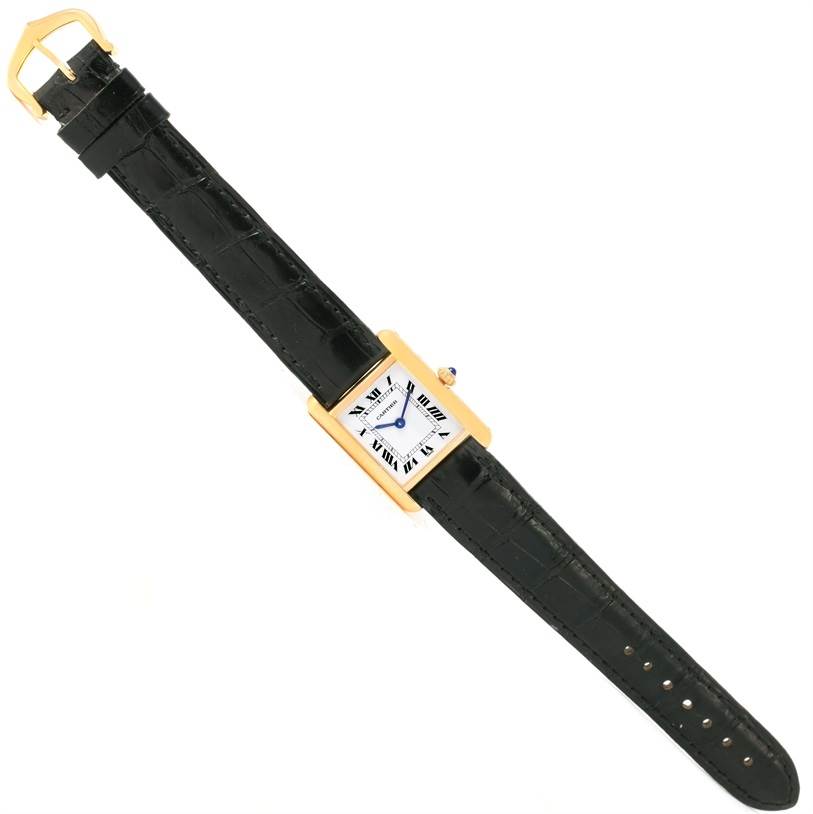 The Cartier Tank Classic Women's Yellow Gold White Dial Women's Yellow Gold White Dial watch is shown from a top-down angle, displaying its face, black leather strap, and gold buckle.