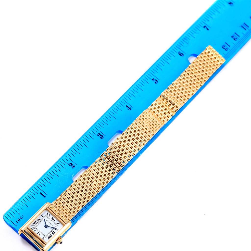 The Tank Classic Cartier watch is shown from a top-down angle, with the face and strap visible alongside a blue ruler for scale.