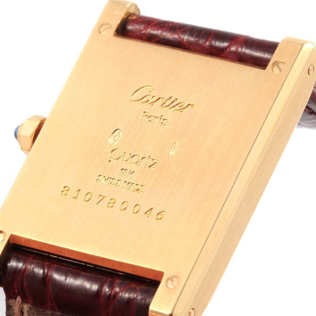 The image shows the back of a Cartier Tank Classic Women's Yellow Gold White Dial Women's Yellow Gold White Dial watch, highlighting the quartz movement stamp and serial number.