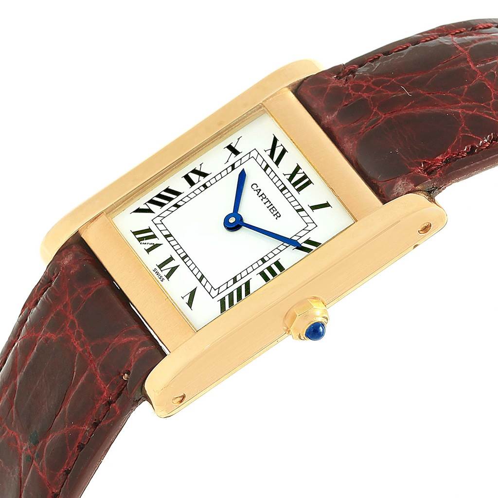 The Cartier Tank Classic Women's Yellow Gold White Dial Women's Yellow Gold White Dial watch is shown at a tilted angle, highlighting its rectangular face, Roman numeral dial, and leather strap.