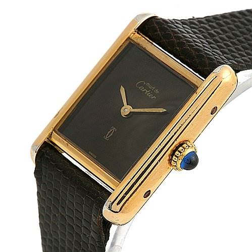 The image shows a Cartier Tank Classic Women's Yellow Gold Brown Dial Women's Yellow Gold Brown Dial watch at an angle highlighting its case, crown with a blue cabochon, and part of the leather strap.