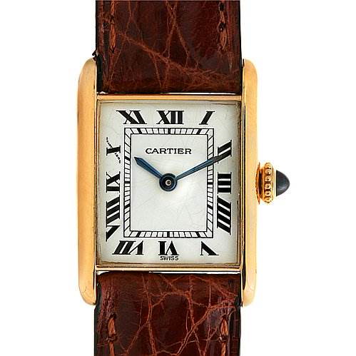 The image shows the face and brown leather strap of a Cartier Tank Classic watch with Roman numerals and a gold case.